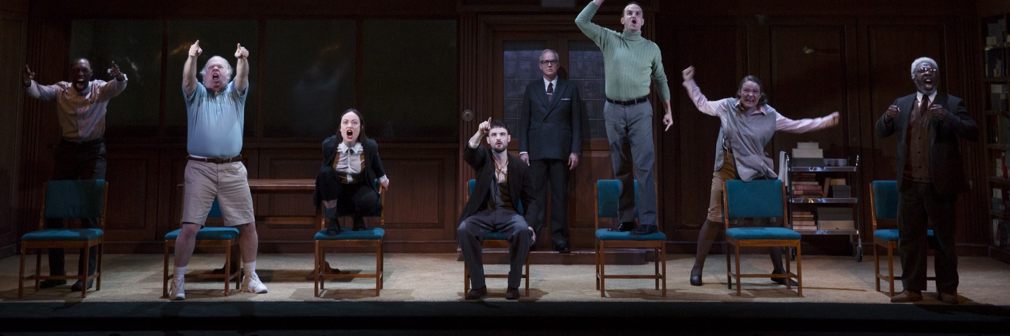 The company of 1984 on stage beneath the telescreen