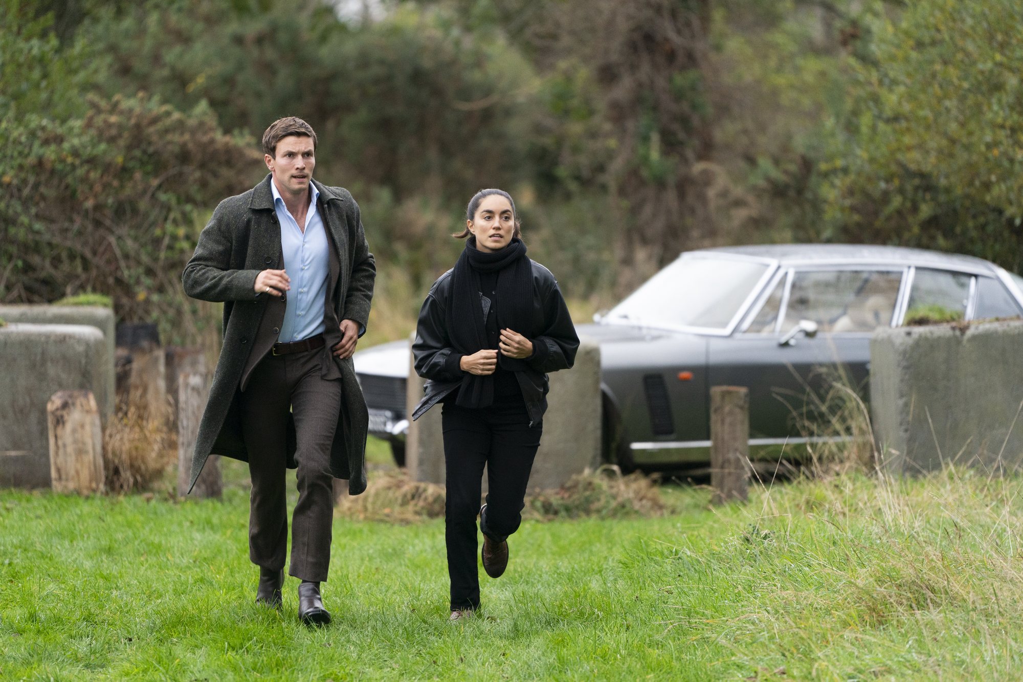Leo Suter and Sofia Barclay as Lynley and Havers, running to the Jensen — Lynley